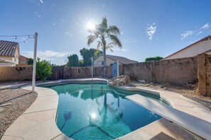 A swimming pool with a curved edge, surrounded by a stone patio and a wooden fence. - Private Pool: Group-Friendly Gilbert Getaway! (Gilbert)