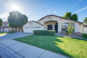 A residential house with a garage, a well-maintained lawn, and a large tree in the front yard. - Private Pool: Group-Friendly Gilbert Getaway! (Gilbert)