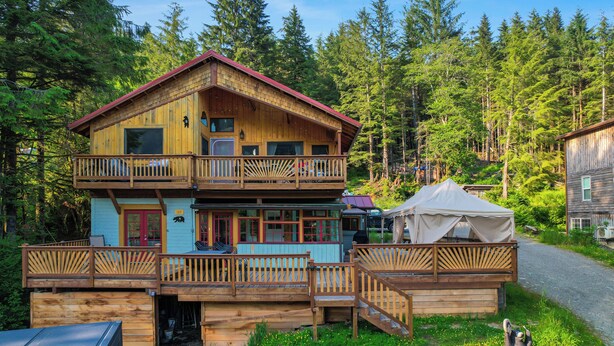 A two-story wooden cabin with a balcony, surrounded by a forest. - Salmon Return & Wildlife Roam: Ketchikan Getaway! (Ketchikan)