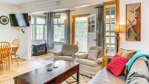 A cozy living room with a fireplace, checkered armchairs, a sofa, and a television. - Salmon Return & Wildlife Roam: Ketchikan Getaway! (Ketchikan)