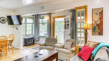 A cozy living room with a fireplace, checkered armchairs, a sofa, and a television.