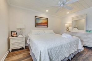 A bedroom with a bed, nightstand, dresser, and a ceiling fan. - Walk to Beach & Marsh: Condo in Murrells Inlet (Murrells Inlet)