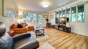 A spacious living room with a large flat-screen TV, a leather sofa, a wooden coffee table, and a fireplace. - 8 Mi to Dtwn Seattle: Pet-Friendly Apt w/ Hot Tub (Mercer Island)