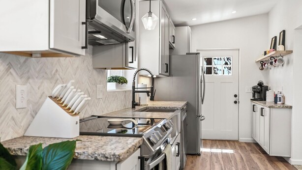 A modern kitchen with white cabinets, a stainless steel range, and a herringbone-patterned backsplash. - Newly Rennovated • Walking Distance to Downtown • Cripple Creek Donkies (Cripple Creek)