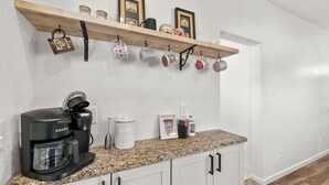 A kitchen with a coffee maker, mugs, and a shelf with framed pictures. - Newly Rennovated • Walking Distance to Downtown • Cripple Creek Donkies (Cripple Creek)