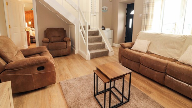 A spacious living room with a staircase, leather sofas, a wooden coffee table, and a view of the outside. - O'CONNELL'S&NBSP;LODGE, pet friendly in Portmagee, County Kerry (Portmagee)