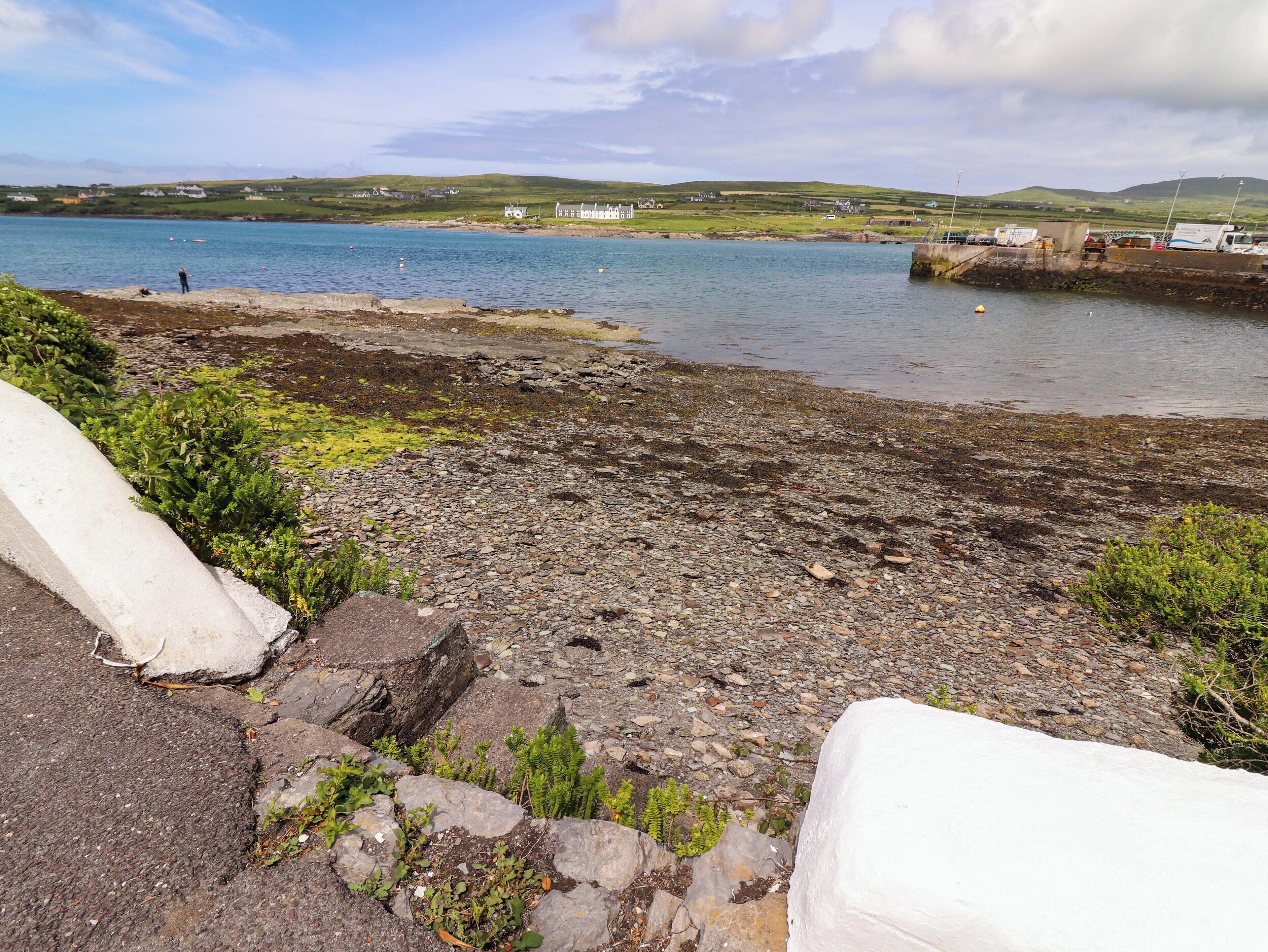 A rocky shoreline with a view of the sea and distant houses.