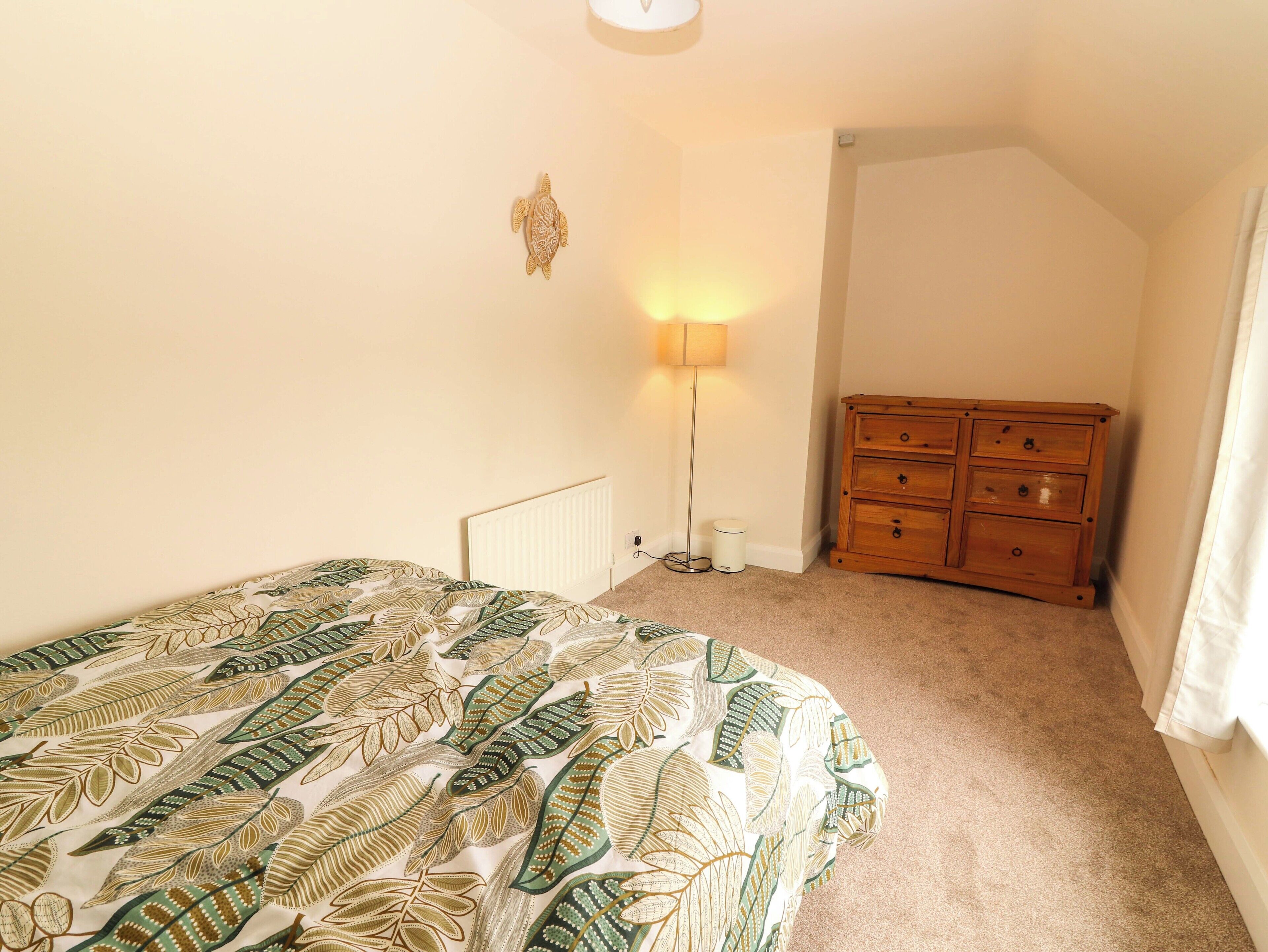 Ein Schlafzimmer mit einem Bett, einem Schminktisch, einem Heizkörper und einer Stehlampe.
