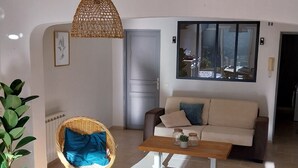A living room with a wicker chair, a sofa, a coffee table, and a hanging light fixture. - Bright house with private pool perfect family vacation (Le Rouret)