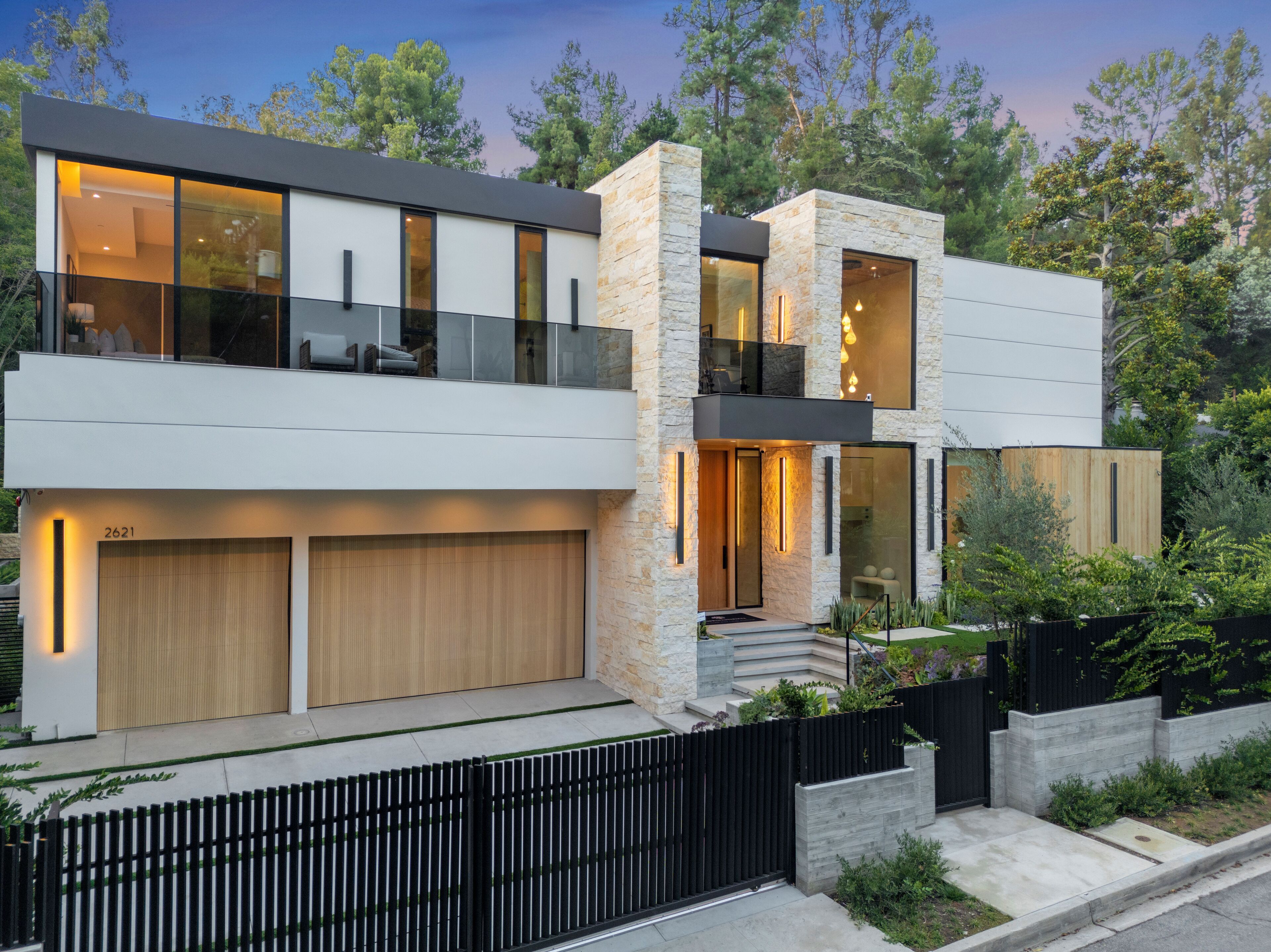 A modern two-story house with a garage, large windows, and a balcony.