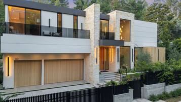 A modern two-story house with a garage, large windows, and a balcony.
