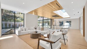 A spacious living area with a large window, a wooden ceiling, and modern furniture. - Hutton Villa - 5-bedroom Retreat in Iconic Beverly Hills Oasis (Beverly Hills)