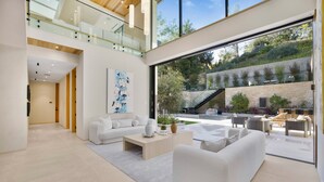 A modern living room with a large glass door leading to an outdoor patio. - Hutton Villa - 5-bedroom Retreat in Iconic Beverly Hills Oasis (Beverly Hills)