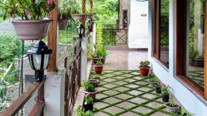 A covered balcony with potted plants and hanging flower baskets. - Mocha Chalet (Nainital)