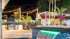 A pool with a waterfall feature, a barbecue grill, and string lights. - Wellness: Pool-Sauna-HotTub-ColdPlunge-Pickleball (Bradenton)