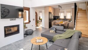 Een moderne woonkamer met een grijze bank, een houten salontafel en een open haard.