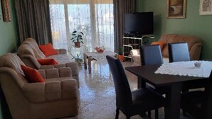 A living room with a sofa, chairs, a table, and a TV.