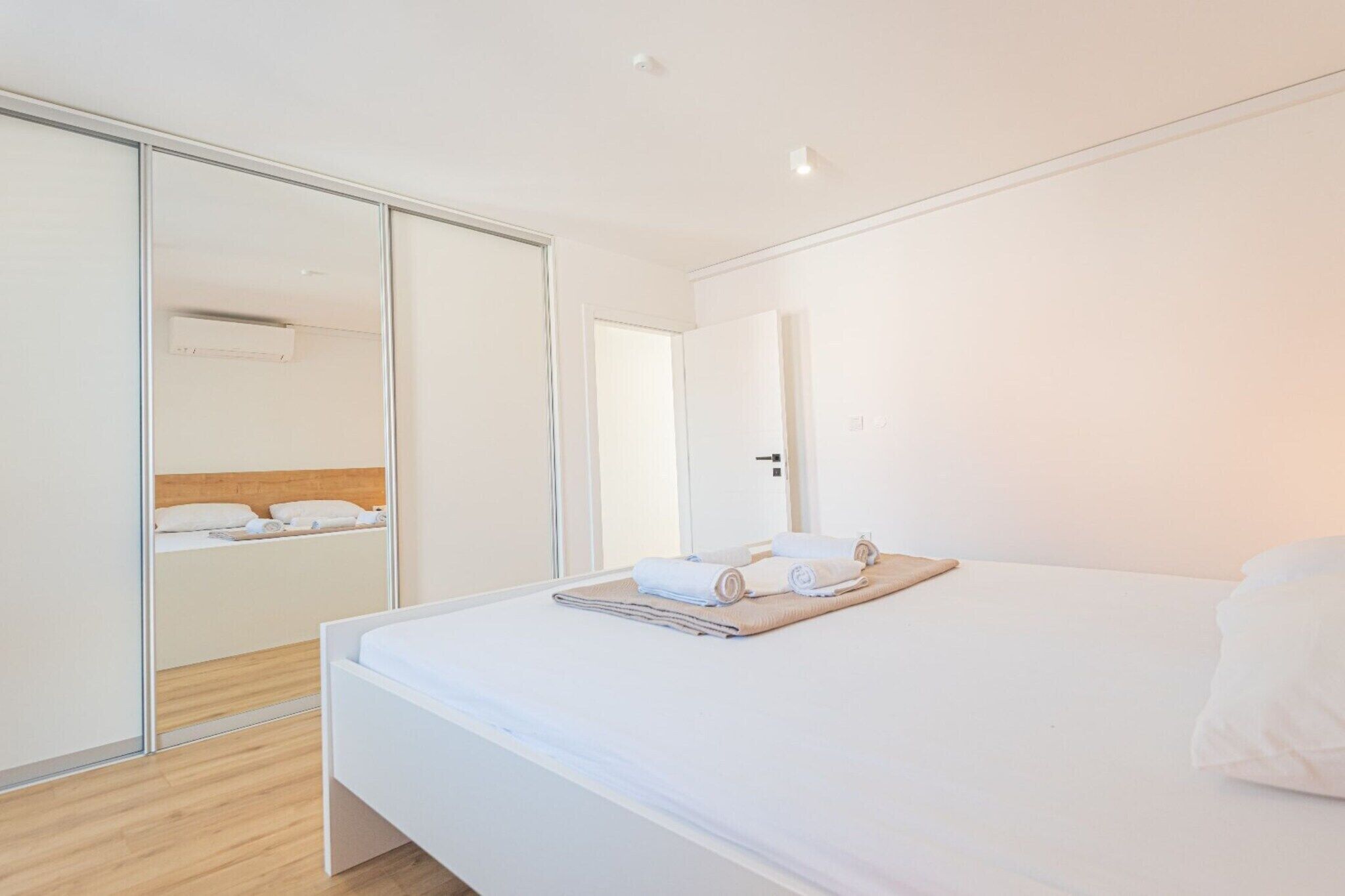A modern hotel room with a large bed, a wardrobe, and a mirror.