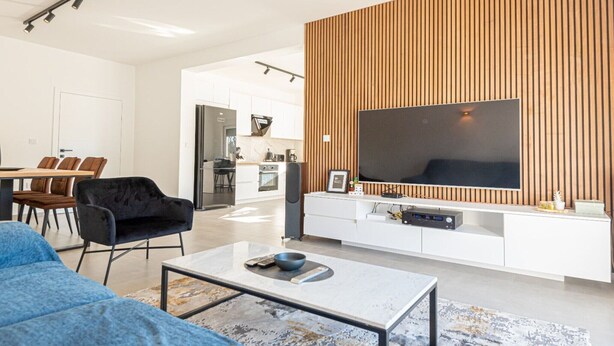 A modern living room with a large flat-screen TV, a sofa, a coffee table, and a dining area in the background. - Holiday Home Iva - Three Bedroom Holiday Home (Šibenik)