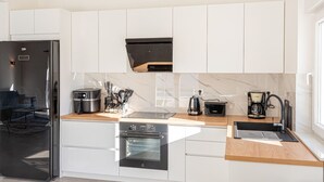 A modern kitchen with white cabinets, a black refrigerator, a built-in oven, a coffee maker, and a toaster. - Holiday Home Iva - Three Bedroom Holiday Home ( Šibenik)