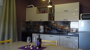 Une cuisine moderne avec un revêtement mural en marbre, des appareils électroménagers intégrés et un coin repas avec une table dressée pour deux personnes.