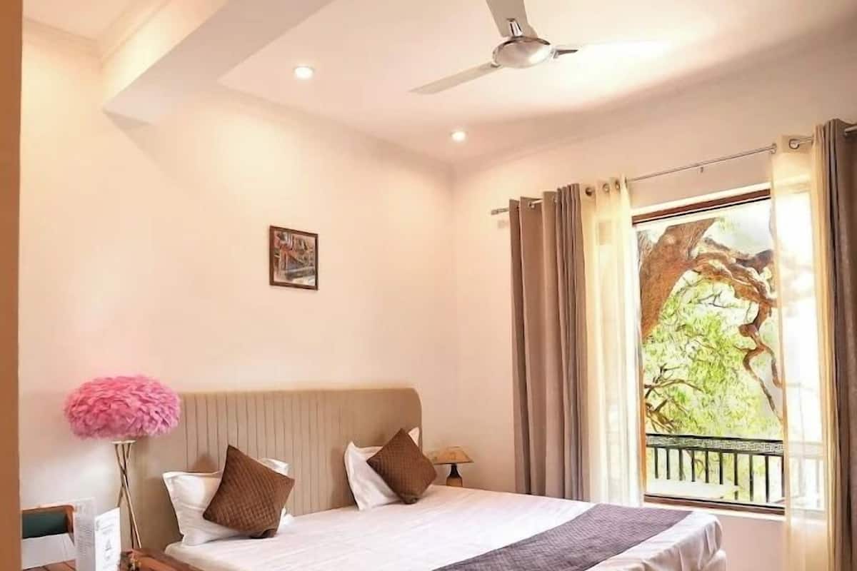 A bedroom with a bed, a desk, a chair, a ceiling fan, and a window with curtains.