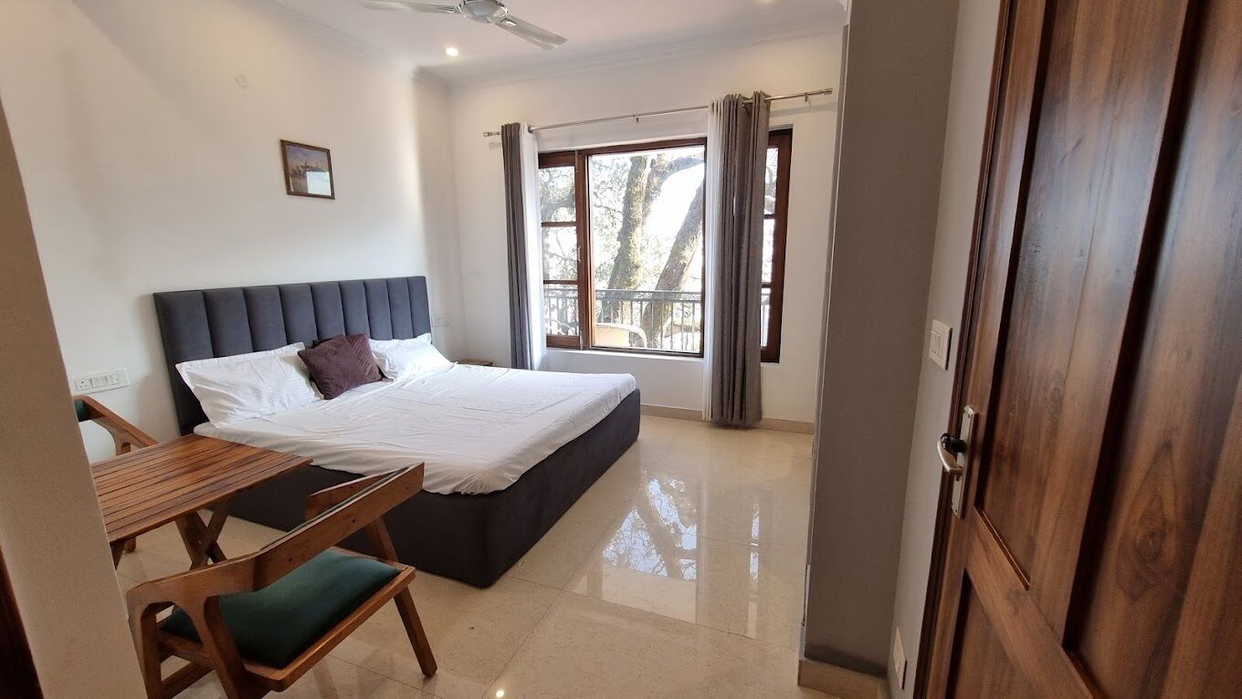A bedroom with a bed, a wooden desk, and a chair.