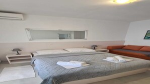 A neatly arranged bedroom with a bed, a nightstand, a lamp, and a sofa.