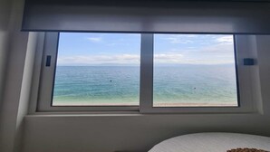 A room with a large window overlooking a beach and the sea.