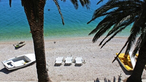 A beach with a row of sun loungers, a small boat, and a yellow watercraft.