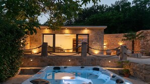 A hot tub in front of a stone building with a glass door, surrounded by a rope barrier and potted plants. - Villa Mia 2 - Six Bedroom Villa with Private Pool (Krivodol)