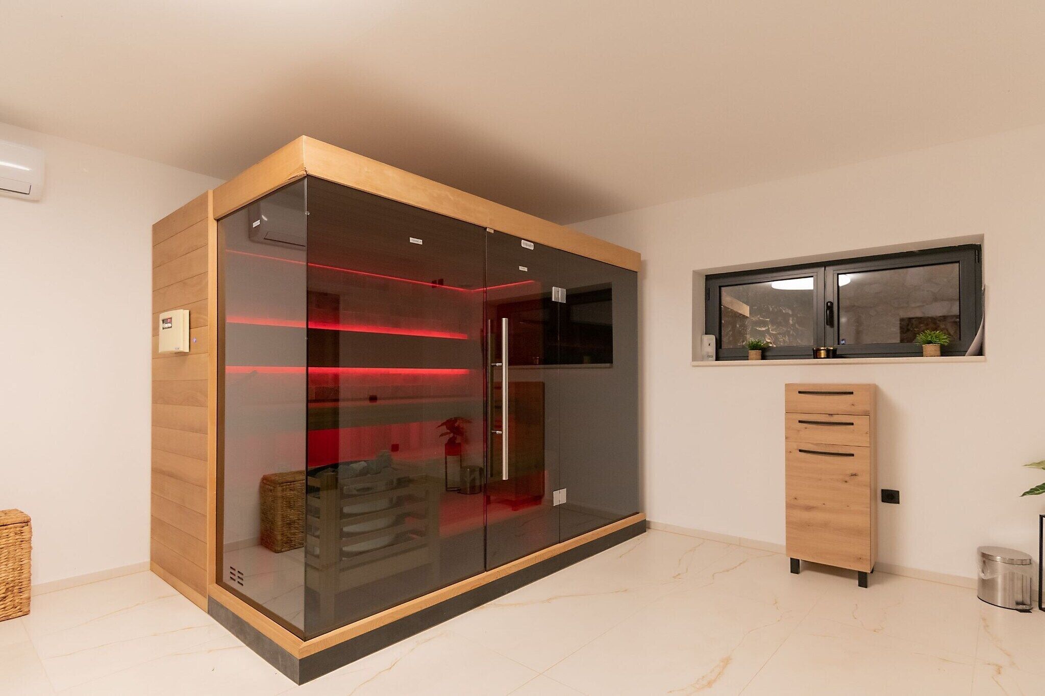 Une chambre moderne avec une armoire en verre, un meuble en bois et une fenêtre agrémentée de plantes.