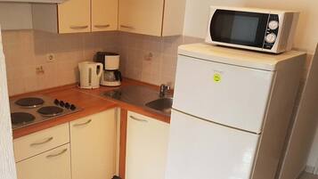 A compact kitchen with a microwave, coffee maker, and a refrigerator.