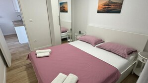 Een slaapkamer met een bed, twee kussens, een nachtkastje en een aan de muur hangend schilderij.