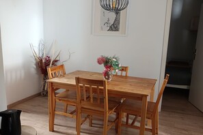 A wooden dining table with chairs, a vase with flowers, and a framed artwork on the wall. - Apartment Analea - Two Bedroom Apartment (Dubrovnik)