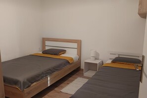 A small, compact room with two single beds, each with a wooden headboard and a bedside table with a lamp. - Apartment Analea - Two Bedroom Apartment (Dubrovnik)
