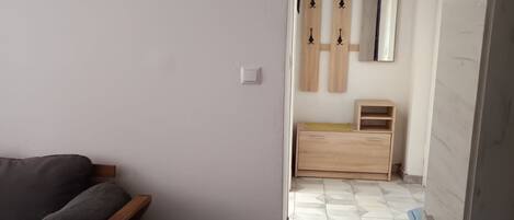 Ein Zimmer mit einem Bett, einem kleinen runden Tisch, einer Holzkommode und einem Spiegel an der Wand.