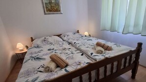 En dubbelsäng med blommigt sänglinne, två sänglampor, ett litet bord med en lampa och en tavla på väggen.