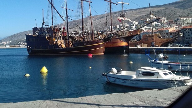 En hamn med båtar, en brygga och byggnader i bakgrunden.