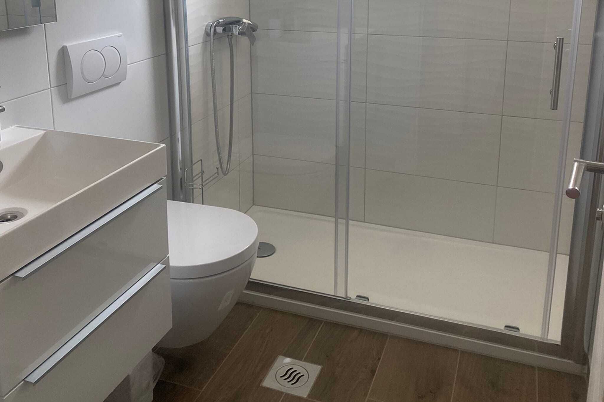A bathroom with a toilet, a shower enclosure, and a sink.