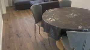 A dining area with a round table, four chairs, and a sofa in the background. - Apartments Danijela & Vlado - Two Bedroom Apartment with Balcony and Garden View (Lopar)
