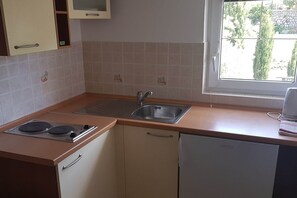 A kitchen with a stove, sink, and window.
