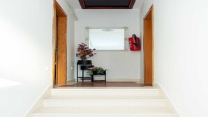 A staircase leading to a landing with a framed picture, a potted plant, and a fire extinguisher.