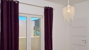 Ein Zimmer mit einer Schiebetür zum Balkon, einer weißen Tür und einer Kristallleuchtre.