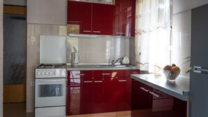 Una cocina con armarios rojos, una estufa blanca y un lavabo.