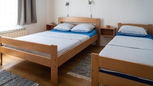 Una cama doble con estructura de madera, dos mesitas de noche, un radiador y una ventana con cortinas.