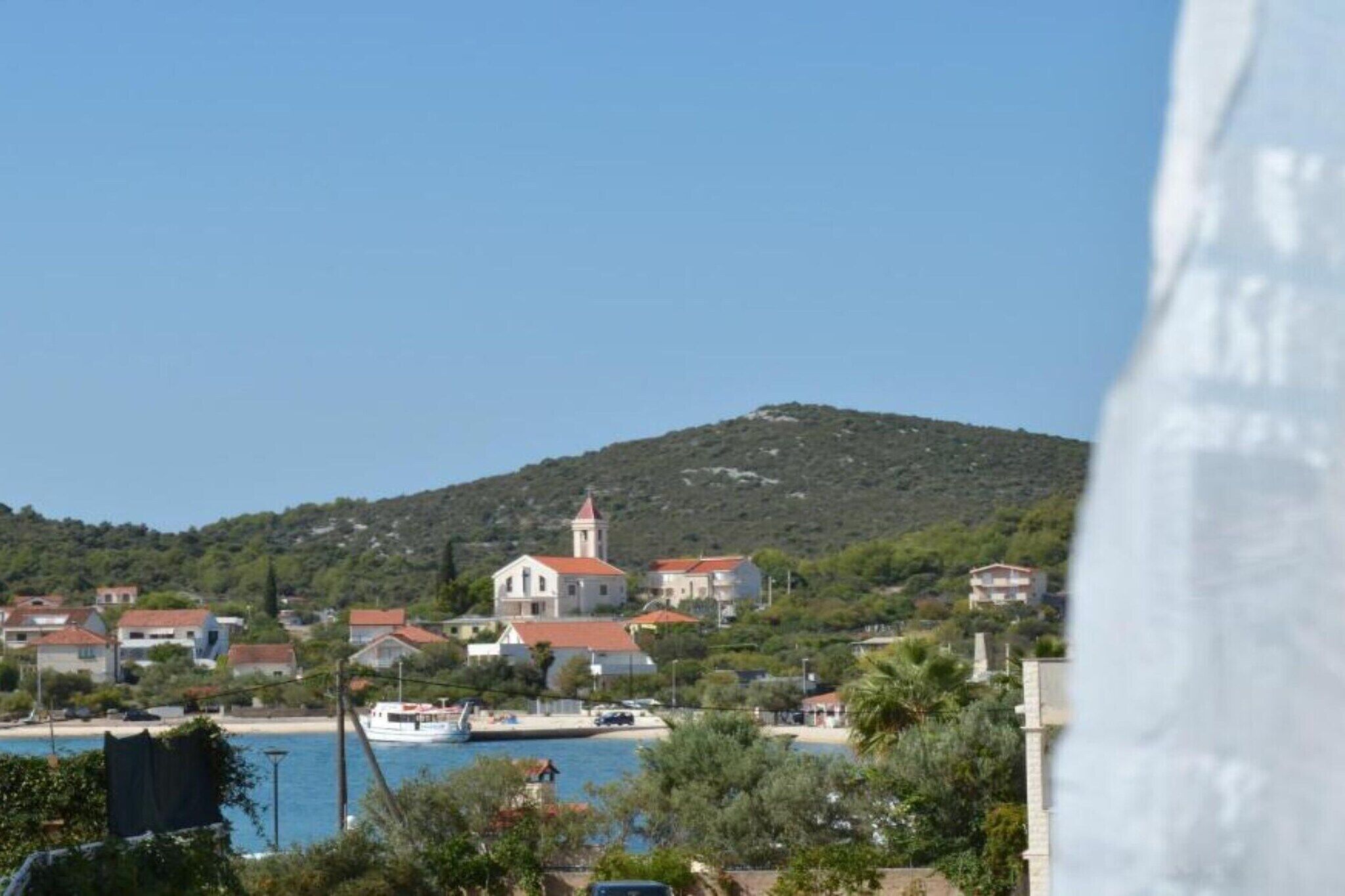 A coastal town with a prominent church on a hill, a body of water, and surrounding residential buildings.