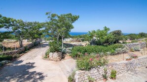 A coastal property with a paved driveway, stone walls, and lush greenery. - Apartments Bonic - Two Bedroom Apartment (Veli Losinj)