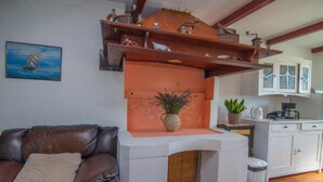 A living room with a brown leather sofa, a white coffee table, a fireplace, and a kitchen area with cabinets and a sink. - Apartments Bonic - Two Bedroom Apartment (Veli Losinj)