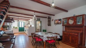 A dining area with a table set for six, surrounded by wooden chairs with red cushions. A wooden cabinet with a mirror is to the right. - Apartments Bonic - Two Bedroom Apartment (Veli Losinj)
